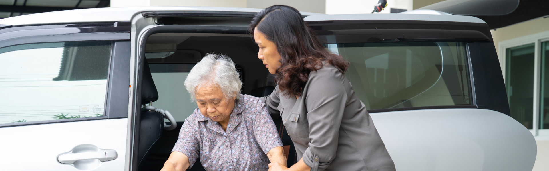 woman assisting elderly get out from the car